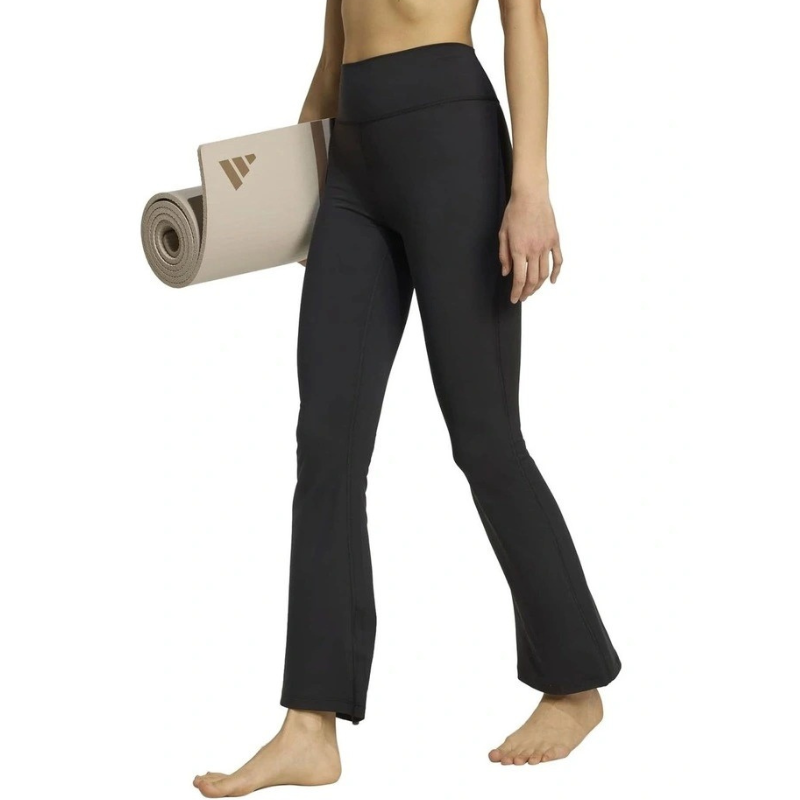Person wearing black yoga pants holding a beige yoga mat with a logo on a white background