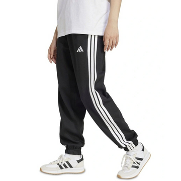 Person wearing black Adidas tracksuit pants with white stripes and white sneakers on a white background