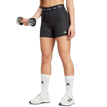 Person wearing black Adidas shorts and white socks holding a dumbbell on a white background