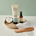Sukin hair care products including a tube, bottle, and comb on a light surface with a neutral background.