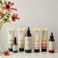 Sukin haircare products on a white surface with flowers in the background