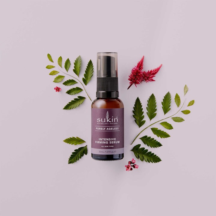 Sukin Intensive Firming Serum bottle with green leaves and red flowers on a light pink background