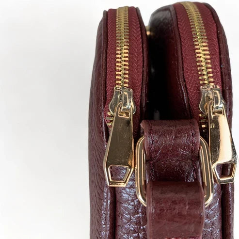 Red leather women’s shoulder bag with three compartments, elegant small satchel design featuring adjustable strap and gold hardware.