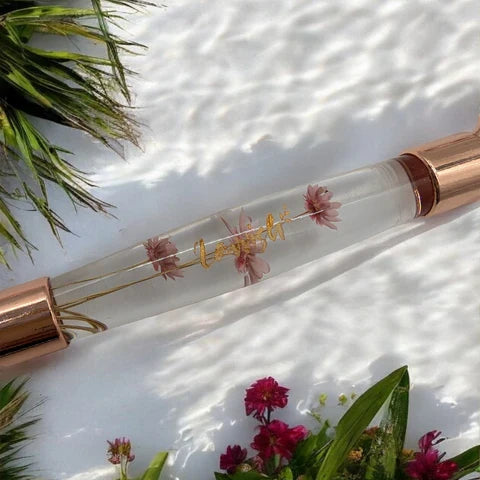 Lavvish Rose Quartz Facial Roller with box displayed on iridescent stand surrounded by small potted succulents