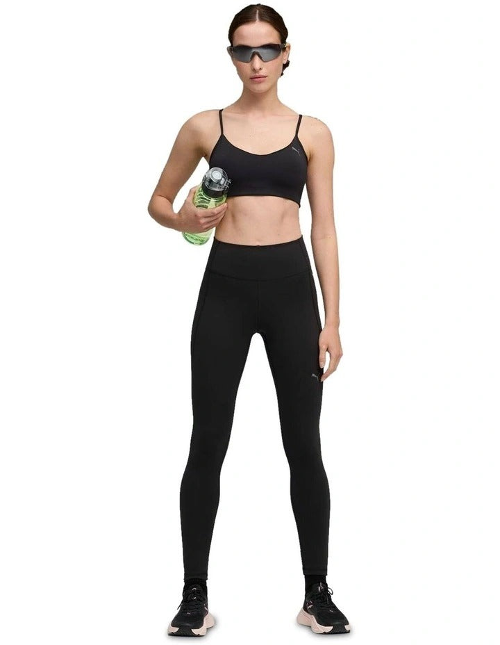 Person wearing black athletic leggings with a small logo on a white background