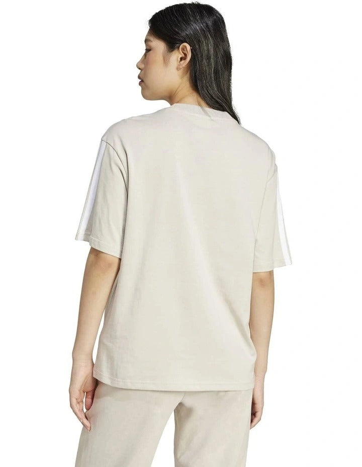 Person wearing a beige t-shirt and pants on a white background