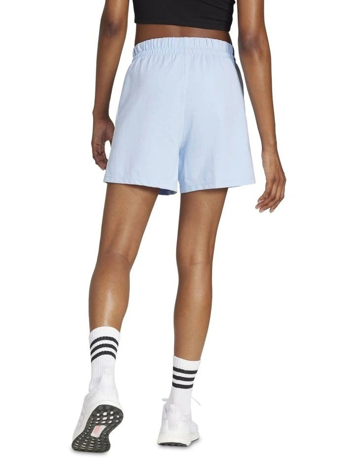 Person wearing light blue shorts and white sneakers on a white background