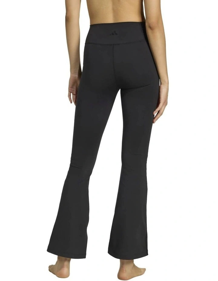 Person wearing black yoga pants holding a beige yoga mat with a logo on a white background