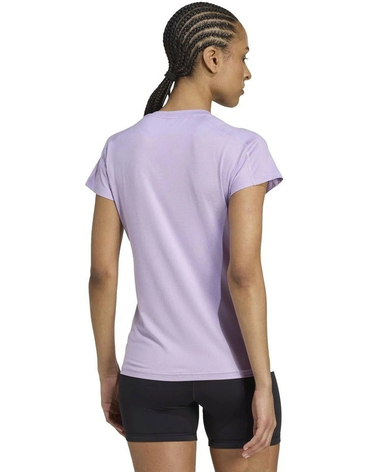Woman wearing a light purple Adidas t-shirt on a white background