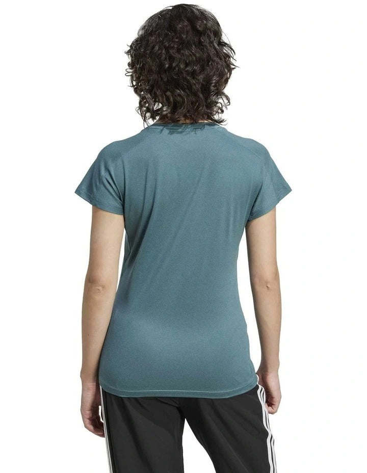 Person wearing a teal Adidas t-shirt and black shorts on a white background