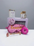 Sleep and Unwind Lavvish gift box with pink eye mask, lavender bath salts, skincare items, and floral soap surrounded by succulents